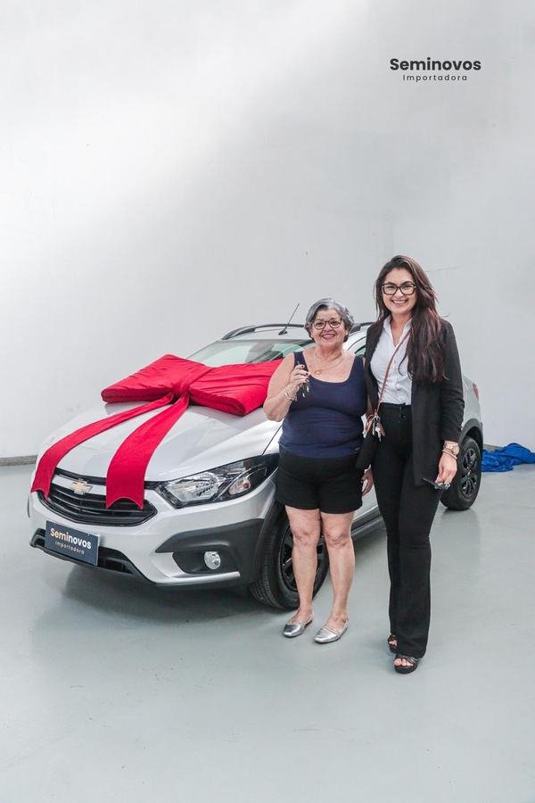 Mariana entregando a chave de um Chevrolet prata a uma cliente
